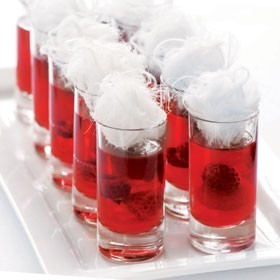 Tray of tall shot glasses filled with red liquid with fairy floss on top
